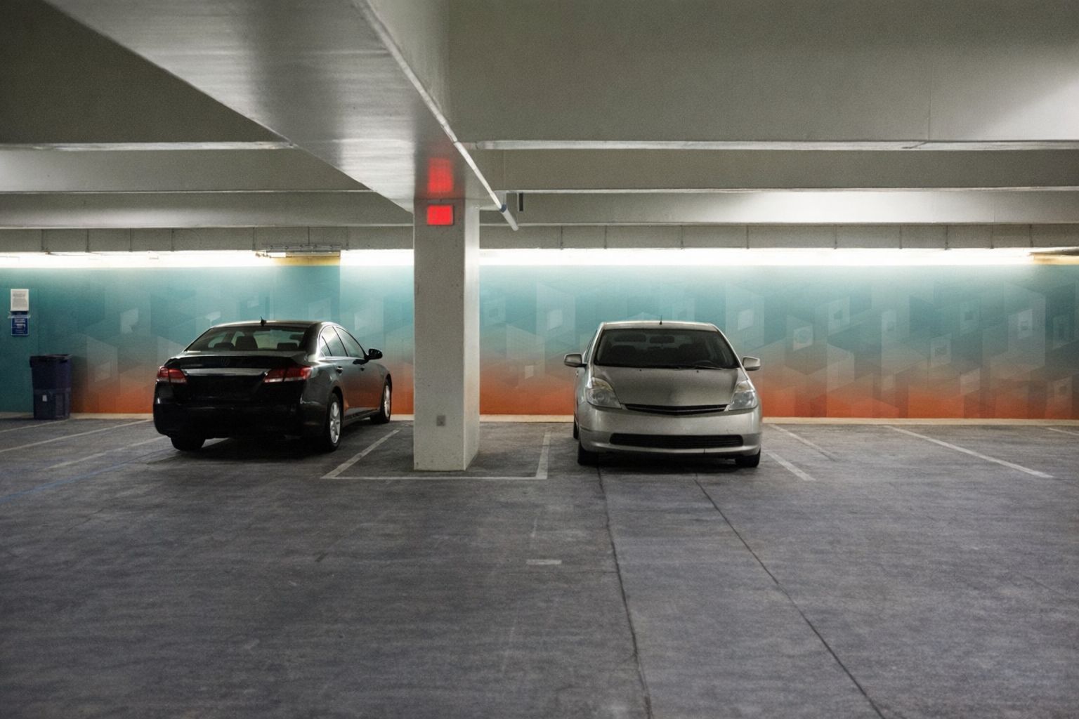 Biler parkeret i et moderne parkeringshus med dekorativ bagvæg.