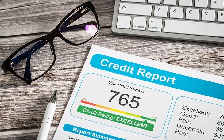 Kreditrapport med score 765 ved siden af briller og tastatur